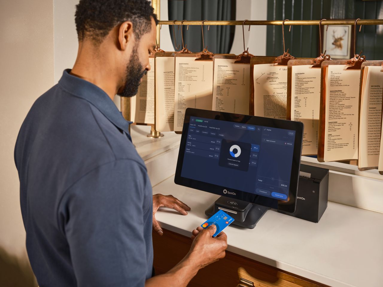Pourquoi sauvegarder ses données est indispensable ? A restaurant staff member uses a POS system to process a credit card payment at the counter.