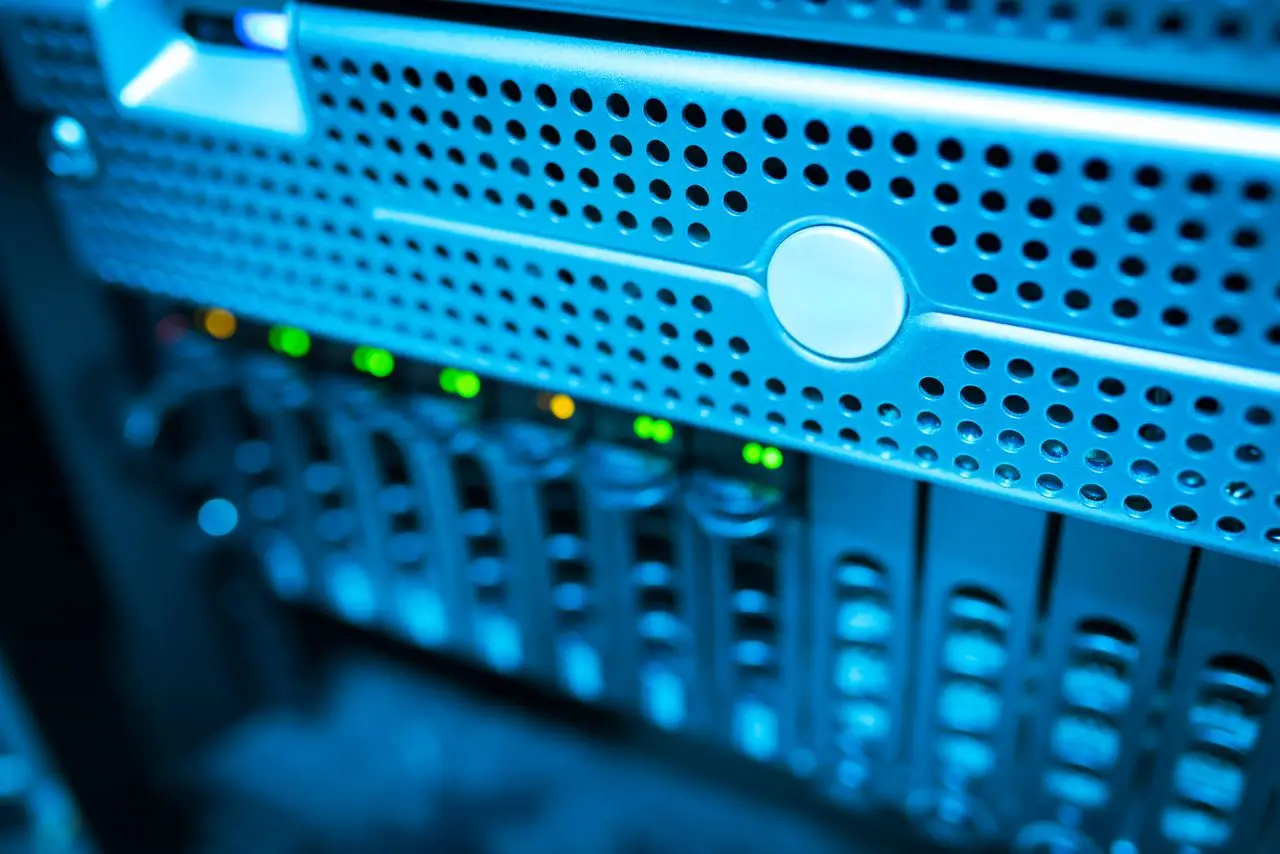 Nos Services Focused view of a modern data server rack with blinking lights in a blue-lit environment.