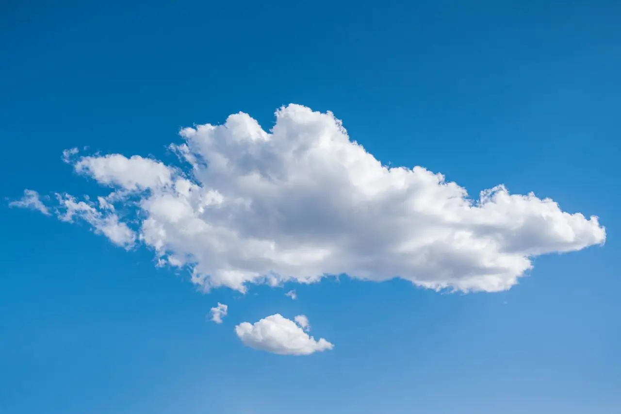From below of white fluffy cumulus clouds floating in bright blue sky on sunny day