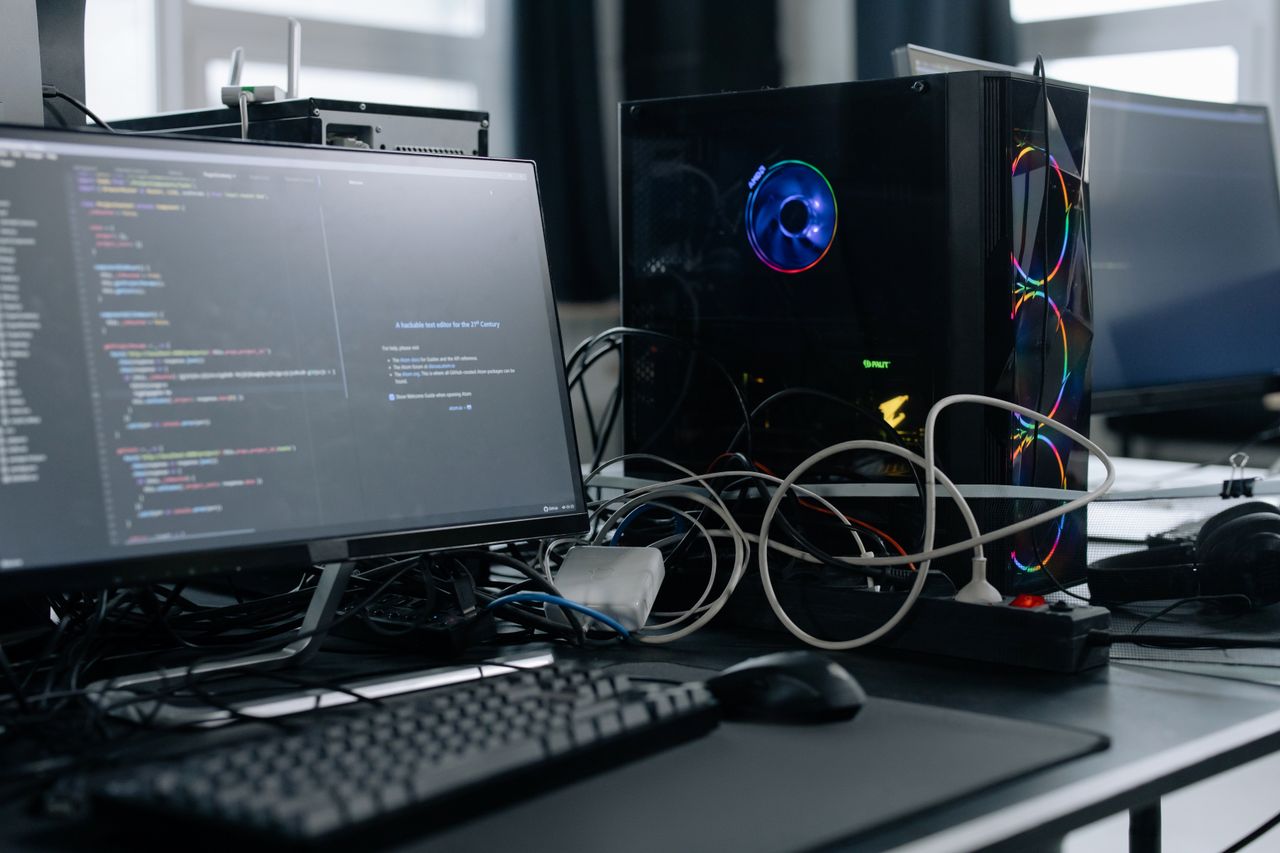 About A modern workspace featuring a computer monitor with code, a PC tower, and peripherals.